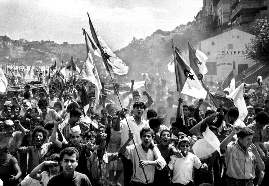 Photograph from Algerian Revolution. Features large group of people waving Algerian flag