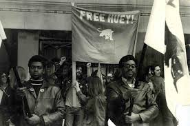 Black Panther Party in Detroit. Photograph includes several party members along with a flag that reads Free Huey!